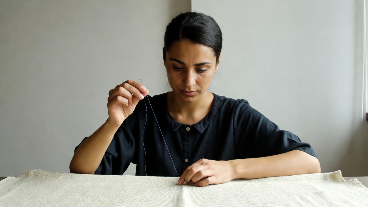 Expert tailor threading a needle